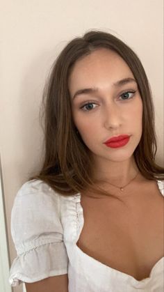 a woman with long hair wearing a white shirt and red lipstick is posing for the camera