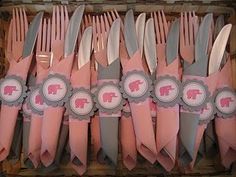 there are many forks and spoons in the box with pink napkins on them