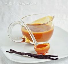 a glass cup filled with liquid on top of a white plate next to an orange peel