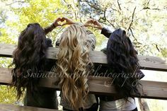 three girls standing on a wooden bench with their hands in the air over their heads