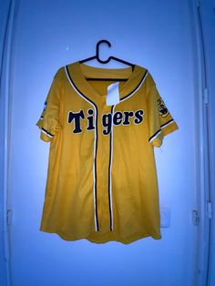 a baseball jersey hanging on a hanger next to a door with the word tigers written on it