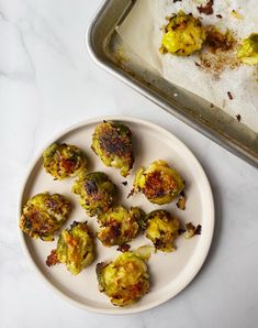 a white plate topped with brussel sprouts next to a baking pan