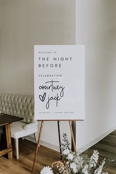 a sign sitting on top of a wooden easel in front of a white couch