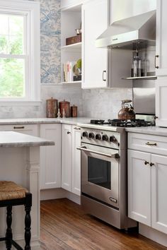 a kitchen with white cabinets and stainless steel stove top oven in the center of the room