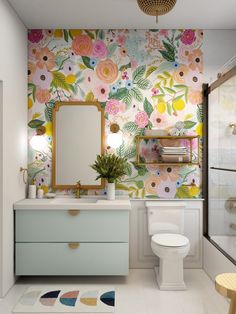 a bathroom with floral wallpaper and a white toilet next to a sink under a mirror