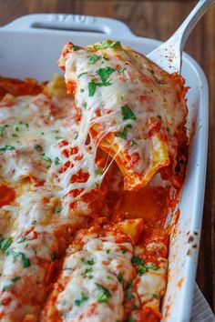 a casserole dish with meat and cheese covered in sauce, garnished with parsley