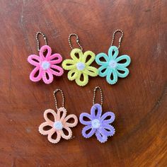 three crocheted flowers are sitting on a wooden table