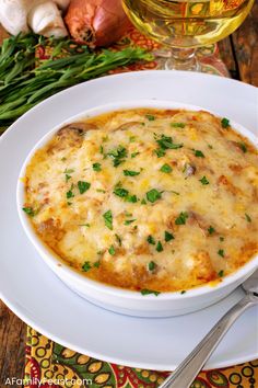 a white bowl filled with food on top of a plate next to garlic and green onions