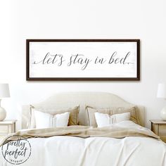 a bedroom with a bed, nightstands and a framed sign that says let's stay in bed