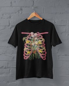 Thanks for stopping by! Grunge skeleton ribs and flowers T-shirt Printed on a super soft, cotton tee Dispatched in 5 working days or sooner Unisex Free UK delivery Material: 100% ringspun cotton. Chest (to fit): S  34/36   M  38   L  40/42   XL  44/46   XXL  48/50 ECO-FRIENDLY Each garment is made to order, reducing extra material and energy that would be otherwise wasted We use DTG printing process which is easier on the environment than screen-printing Our ink is bright and also eco-friendly. Spring Grunge T-shirt For Alternative Fashion, Alternative Style T-shirt For Spring Streetwear, Casual Spring T-shirt For Alternative Fashion, Spring Punk Fitted T-shirt, Spring Punk Style Fitted T-shirt, Spring Grunge Fitted T-shirt, Spring Skull Print Short Sleeve T-shirt, Spring Band Merch Tops With Graphic Design, Unisex Pink T-shirt With Band Merch