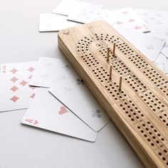 a wooden board with holes in the middle and playing cards around it on a table