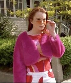 a woman in pink sweater and white pants talking on cell phone