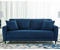 a blue couch sitting on top of a rug in a living room next to a lamp