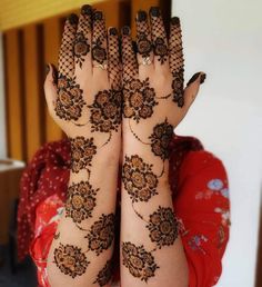 a woman's hands with hennap on her arm and hand holding something in the air