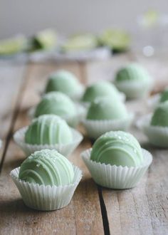 green chocolates are lined up on a wooden table