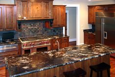 a kitchen with granite counter tops and wooden cabinets, along with an island in the middle