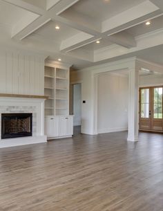 an empty living room with hard wood floors and white painted walls, built in bookcases