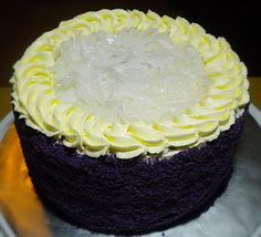 a cake with white frosting and yellow icing sitting on a silver platter