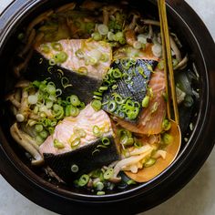 fish and vegetables in a bowl with chopsticks