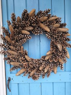 a wreath made out of pine cones on a blue door