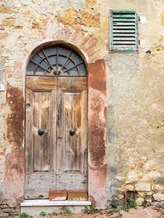 an old building with two wooden doors and shutters