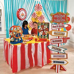 two children sitting at a table with carnival signs