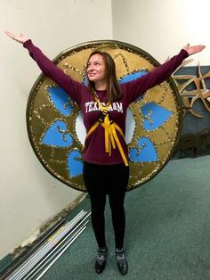 a woman standing in front of a large shield