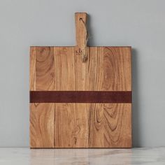 a wooden cutting board with a brown strip on the edge and a gray wall in the background