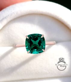 a ring with a green stone in it on top of a white cushioned surface