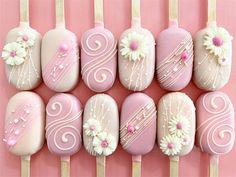 pink and white decorated nails with flowers on them are arranged in rows against a pink background