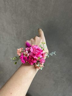 a woman's arm with pink flowers and greenery on it, against a gray background