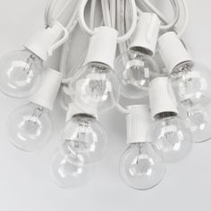 a bunch of light bulbs sitting on top of a white table next to a cord