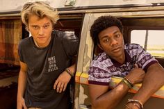 two young men leaning on the back of a truck