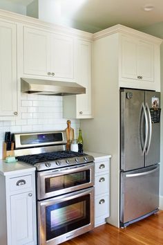 a kitchen with white cabinets and stainless steel appliances