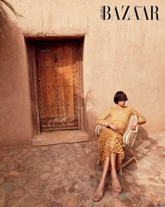 a woman sitting on a chair in front of a door with the word bazaar written above it