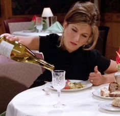 a woman pouring wine into a plate with food on it