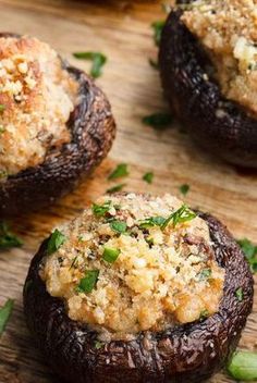 three stuffed mushrooms on a cutting board with parmesan cheese and seasoning sprinkles