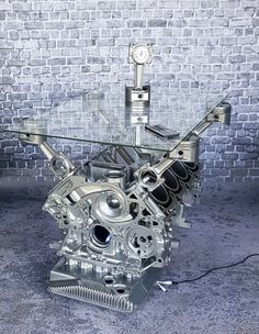 a metal engine sitting on top of a glass table in front of a brick wall