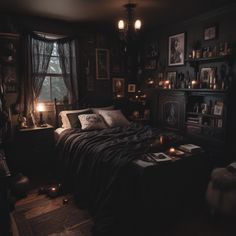 a bed in a dark room with pictures on the wall and candles lit around it