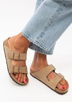 Comfortable and fashionable, the Arizona Sandal by Birkenstock conforms to your foot and you'll never want to take them off. We're wearing them with denim and a soft cashmere sweater for the colder months. Features include two adjustable straps, cork footbed, a flat heel, soft and flexible suede upper with a metal stud design, and soft lining that molds to your foot. Suede Upper | Suede Footbed Cork Base EU Sizing (size 37 corresponds to US size 6) Made in Germany Fit runs true to size, we recom Birkenstock Arizona Taupe Outfit, Arizona Birkenstock Outfit, Birkenstock Arizona Outfit, Birkenstock Suede Arizona, Germany Fits, Taupe Outfit, Comfortable Leather Sandals, Birkenstock Outfit, Birkenstock Sandals Arizona