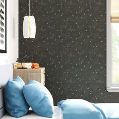 a bedroom with black and white stars on the wall, blue bedding and pillows