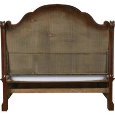 an antique wooden bed frame with white sheets