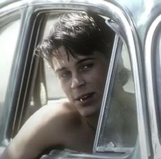 a shirtless young man sitting in the driver's seat of a car