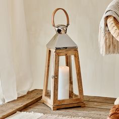 a wooden lantern with a lit candle in it on a rug next to a window