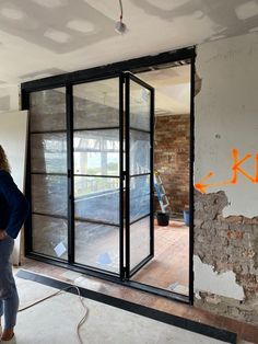 a woman standing in front of a glass door with graffiti on the wall behind her