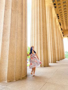 a woman in a dress is standing between two columns and looking up at the sky