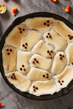 a cast iron skillet filled with marshmallows and topped with ghost s'mores