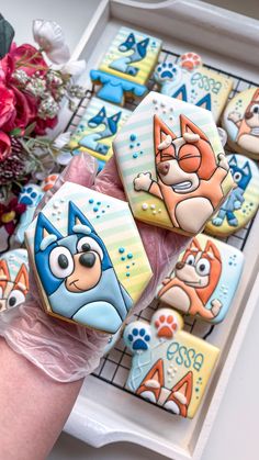 decorated cookies with cartoon characters on them sitting on a tray next to flowers and vases