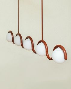 three lights hanging from the ceiling in a row with one light on each side and two white balls at the end