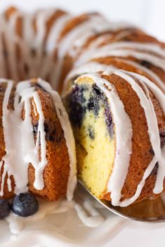 a blueberry bundt cake with white icing and fresh blueberries on the side